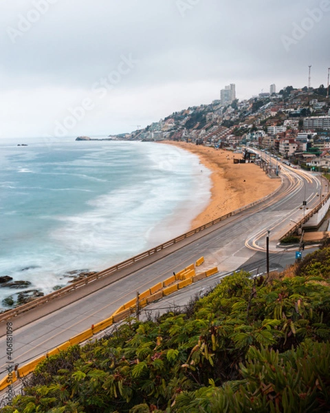 Fototapeta Vista panorámica desde el mirador de Reñaca con olas chocando contra la playa y los autos pasando dejando una silueta