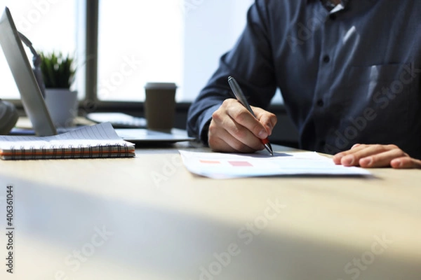 Fototapeta Businessman writes in a notebook while sitting at a desk.