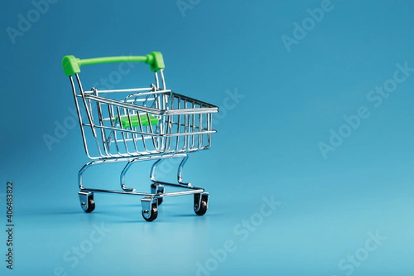 Obraz An empty supermarket cart on a blue background.