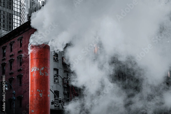 Fototapeta Close up view of the white-orange striped vent releasing steam on the street/ Old and modern buildings in the background.
Manhattan, New York, USA