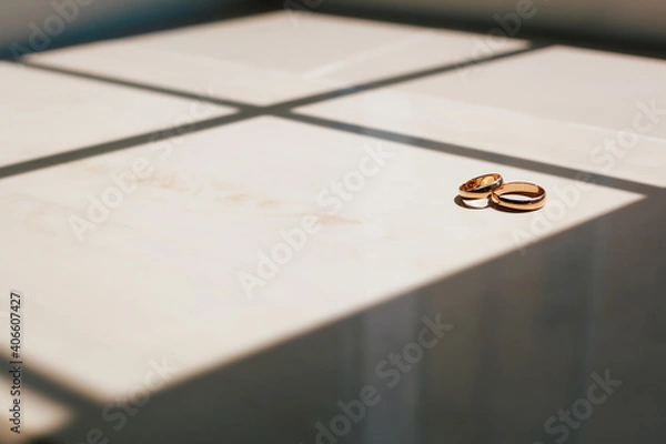 Obraz Beautiful wedding rings lie on wooden surface against background of bouquet of flowers. Declaration of love, spring. Wedding card, Valentine's Day greeting. Wedding rings. Wedding day details