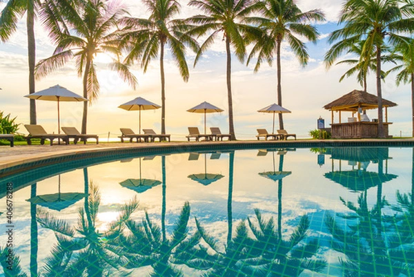 Obraz Beautiful luxury umbrella and chair around outdoor swimming pool in hotel and resort with coconut palm tree on sunset  or sunrise sky