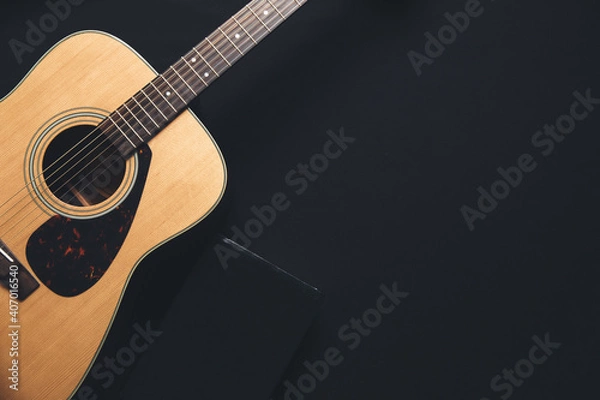 Fototapeta A guitar and a bible on a black background in a dimly lit environment. Soft light and worship