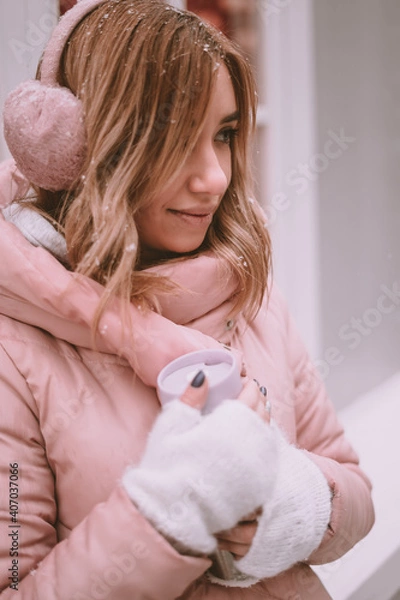 Obraz a girl on the street in winter holds a thermos in her hands and smiles mysteriously