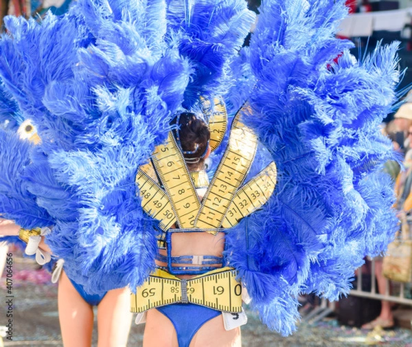 Fototapeta Dancers wearing colorful feathers costumes gathered for a parade. Back view blurry defocused unrecognisable crowd image great for graphic background.