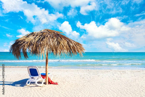 Fototapeta Relaxation and vacation idyllic background. Straw umbrella with sun lounger and red towel on the beach in Varadero, Cuba.