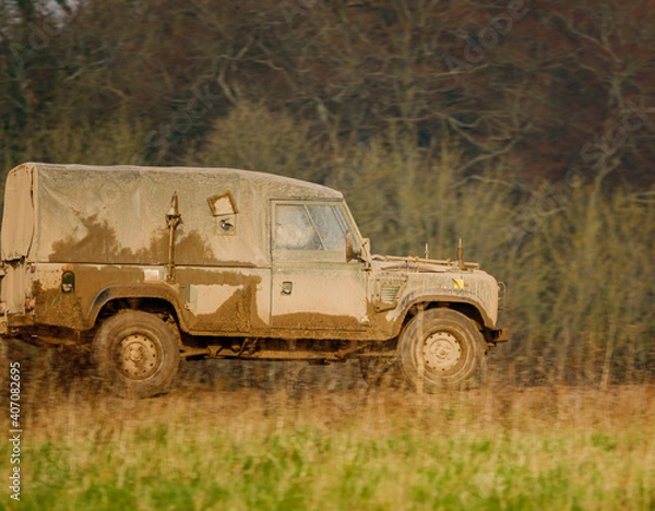 Obraz mud covered army land rover defender 4x4 driving along a track