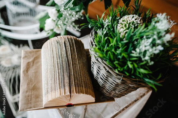 Fototapeta Table for wedding ceremony is decorated with flowers, books and greens, greenery. Close up. Artwork in style vintage.