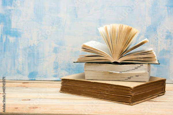 Fototapeta Composition with vintage old hardback books, diary, fanned pages on wooden deck table and red background. Books stacking. Back to school. Copy Space. Education background.