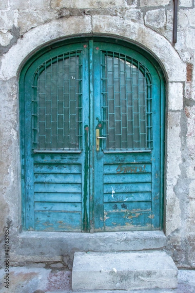 Fototapeta Beautiful vintage blue painted door. Blue grunge wooden door in brick wall. Old rustic wooden doors in Montenegro, Europe