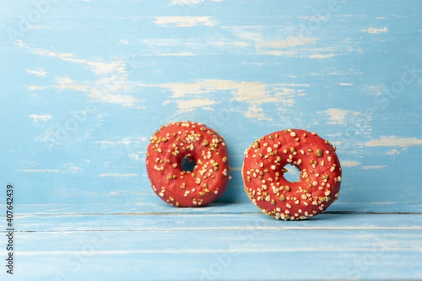 Obraz Two red donuts on rustic blue wooden background