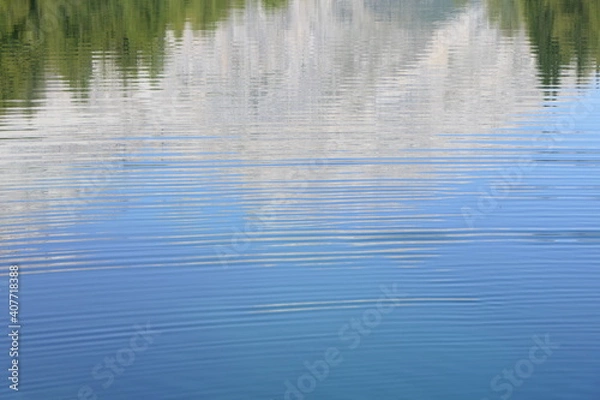 Fototapeta Wallpaper with water rings and a gentle reflection of forests and mountains in blue lake