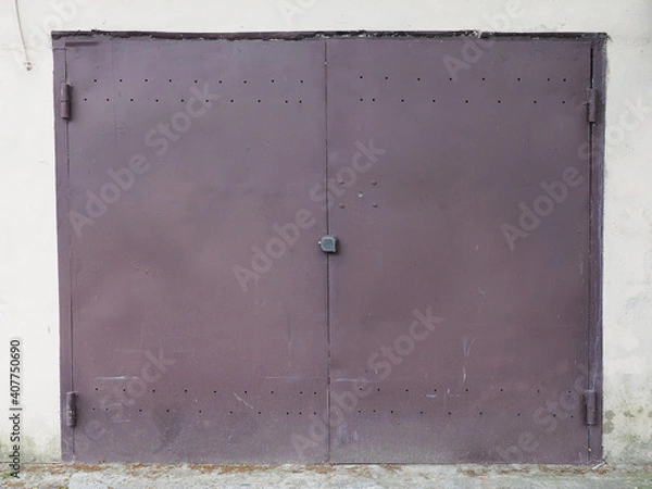 Fototapeta Closed iron brown garage door with holes at the top and bottom and splashing mud
