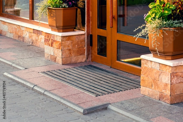 Obraz threshold with a foot mat at the front door with a stone facade and flowerpots, closeup architecture.