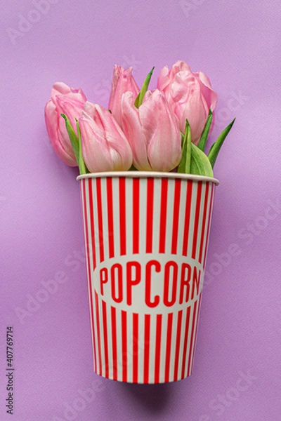 Fototapeta Tender pink tulips inside of red striped popcorn cup on pastel violet background. Flat lay. Copy space. Place for text. Concept of international women's day. Valentines love day