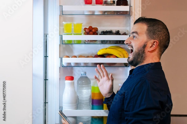 Fototapeta Surprised man looking inside the fridge