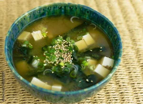 Fototapeta Miso soup with silken tofu, wakame seaweed, scallions and sesame in a green bowl.