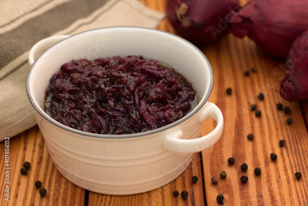Fototapeta Red onion relish homemade with balsamic vinegar and brown sugar in a white ceramic dish standing on a wooden background.