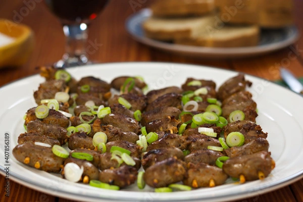 Fototapeta Chicken heart skewers cowered in scallions on a plate