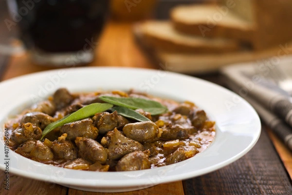 Fototapeta Stewed chicken hearts on a white plate garnished with sage.