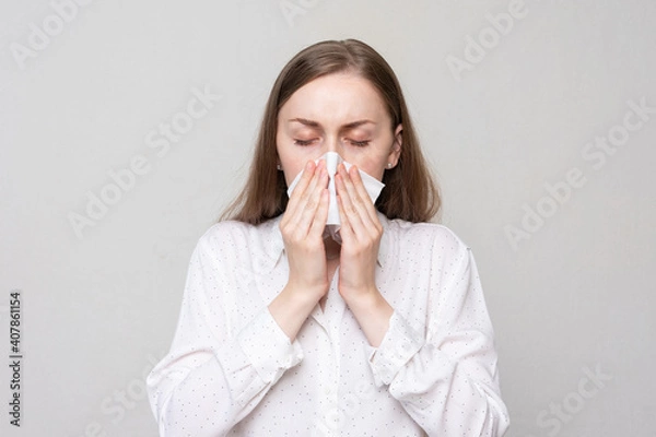 Obraz Sick girl blowing nose into tissue, portrait, white background, closeup