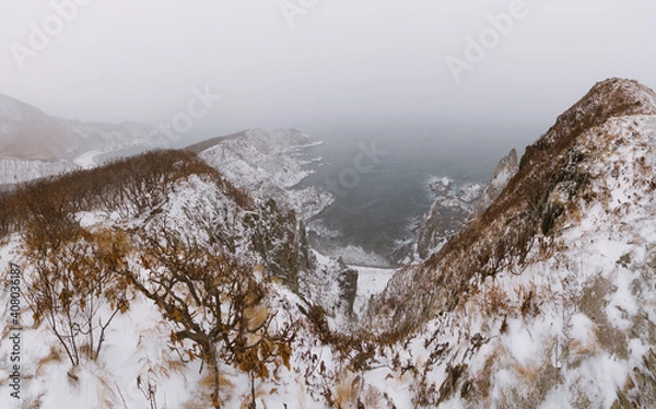Fototapeta Snow storm over sharp sea cliffs
