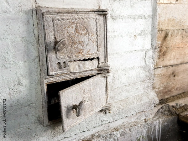 Fototapeta Two old iron doors of the firebox and ash-pan in a Russian stove, whitewashed with lime, in a country house.