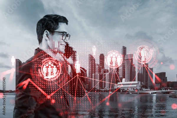 Fototapeta A young handsome eastern businessman processing conference call to develop social media marketing strategy to achieve business goals. Hologram icons over Singapore background.