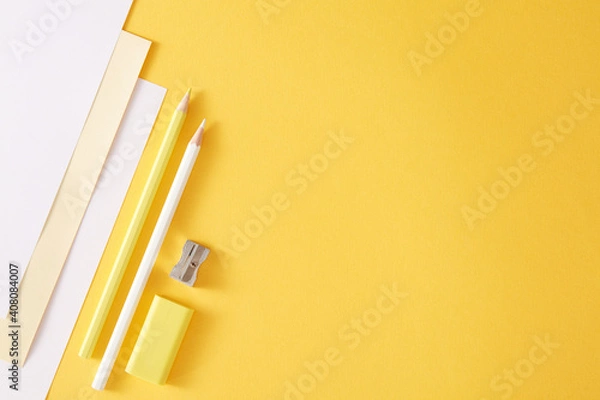 Fototapeta Yellow and white pencils, white papers and metal pencil sharpener. Empty place for text or drawing on the yellow background.