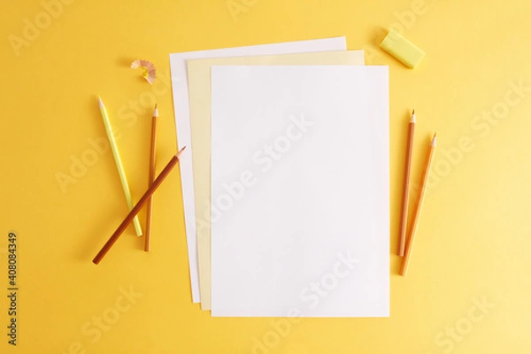 Fototapeta Colorful pencils, eraser and empty white papers . Empty place for text or drawing on the yellow background..