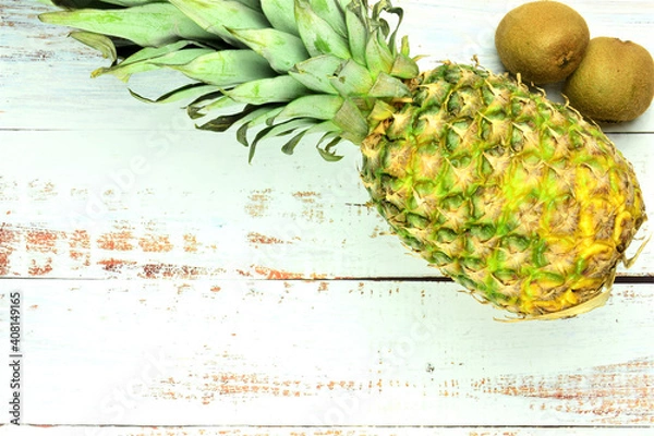 Fototapeta Tropical fruits on rustic white table, pineapple and kiwis.