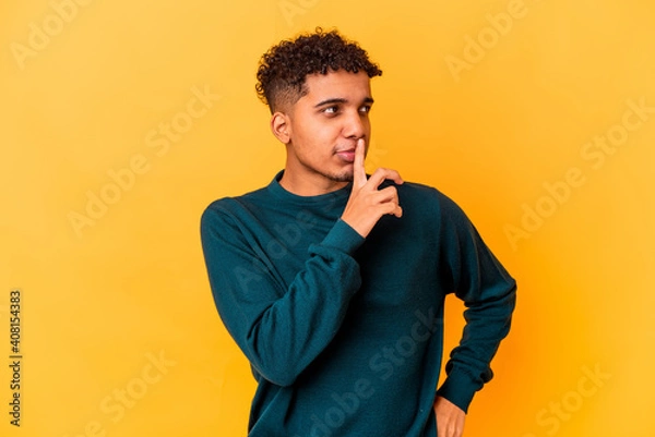 Fototapeta Young african american curly man isolated on purple looking sideways with doubtful and skeptical expression.