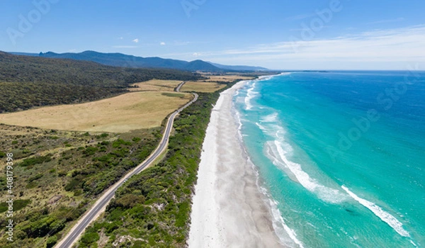 Fototapeta Stunning high angle aerial panoramic drone view of Denison Beach and the A3 Tasman Highway just north of the village of Bicheno on the east coast of Tasmania, Australia on a sunny day.