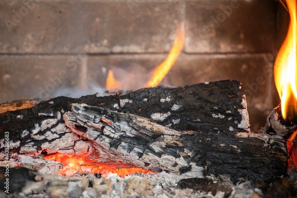 Fototapeta flaming fire in an extinguished stone fireplace, horizontal