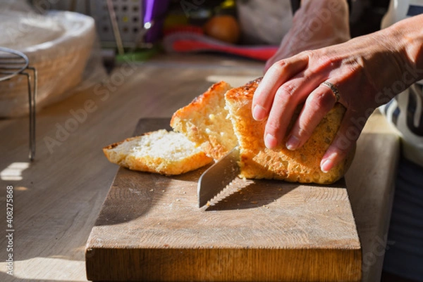 Fototapeta women's hands cut freshly baked bread at home