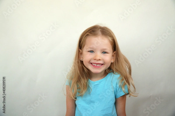 Fototapeta Cute little girl shows emotions on a white background in a T-shirt. Simple beauty. High quality photo