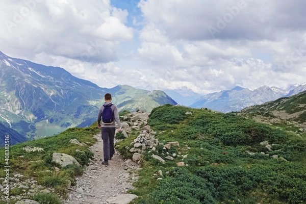 Fototapeta Man with a backpack hiking in summer mountains.