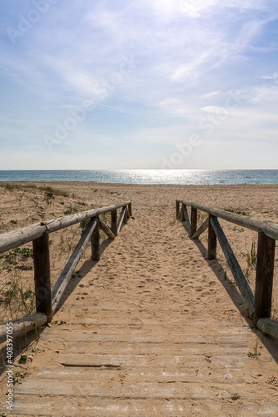 Fototapeta wooden boardwalk and beach access leads directly onto beach with glistening calm ocean behind