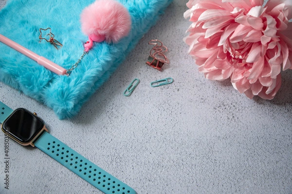 Fototapeta Fluffy diary with cute pink pen and some office supplies on a table. Pink dahlia flower in a corner