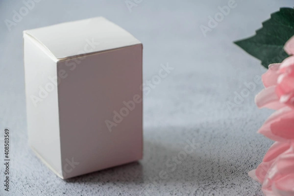 Fototapeta White box on a gray background with pink dahlia flower in a corner. Product concept