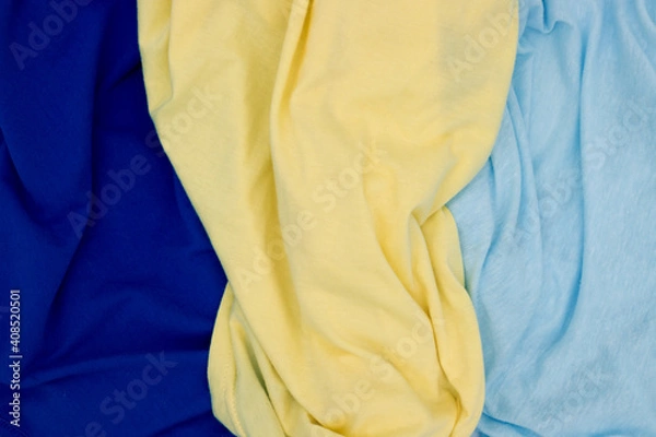Fototapeta Blue yellow fabric top view. Bright colored textile photo texture. Folded fabric with wrinkles for pattern mockup. Blank textile surface. Fashion or retail industry banner template