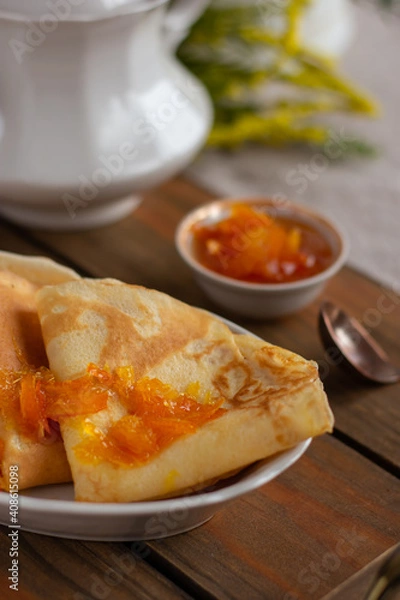 Fototapeta Thin pancakes with orange jam or marmalade on wooden background. Tasty breakfast. Maslenitsa.