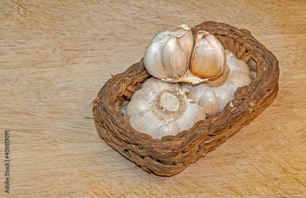 Fototapeta Healthy and wholesome food. 
Fresh garlic in a wicker basket on a wooden table.
Selective focus.
Top side view.