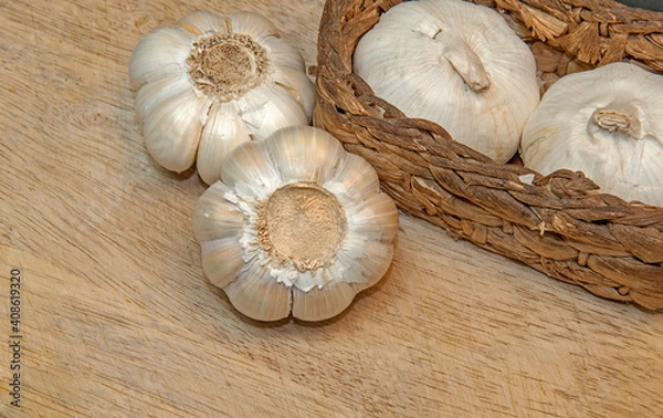 Fototapeta Healthy and wholesome food. 
Fresh garlic in a wicker basket on a wooden background.
Selective focus.
Top side view.
