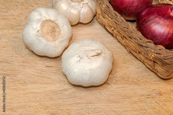 Fototapeta Organic garlic and red onion in wicker basket on light wooden table background with copy space for text, selective focus.
Top view.