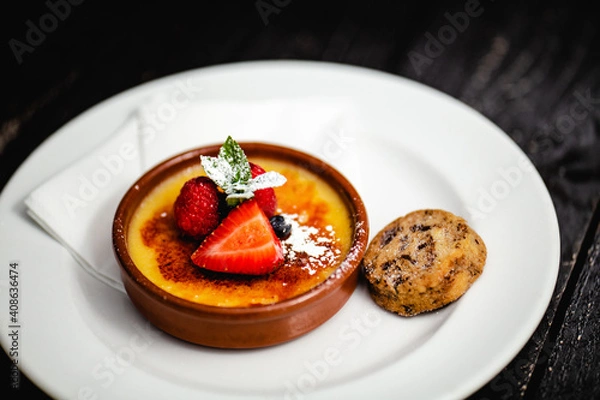 Fototapeta Lemon Creme Brule topped with summer berries, served with a dark chocolate shortbread