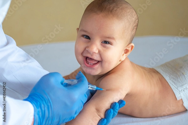 Fototapeta A doctor giving a vaccine to a baby in the hand close-up. The child is happy and smiling