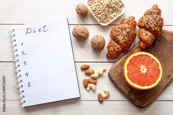 Fototapeta Diet plan on white wood background. Organic food: grapefruit, cereal, nuts and bakery products, top view