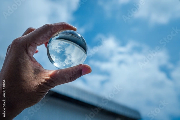 Obraz The hand was holding a glass ball and shone at the blue sky.