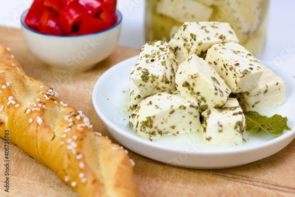 Fototapeta Artisan soft sheep cheese made on a Slovak farm marinated in a salty brine with herbs a bay leaf. Presented on a white plate with a bread roll. 